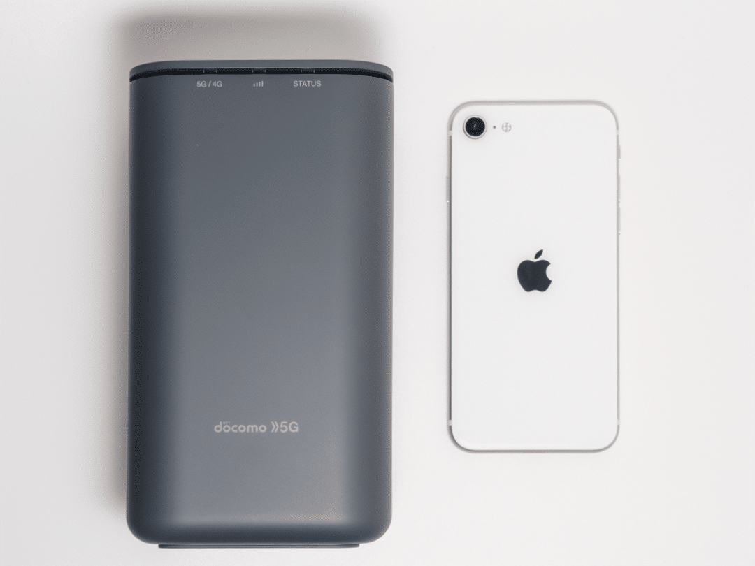 home 5G HR01正面とiPhone SE。けっこうコンパクトな印象です。